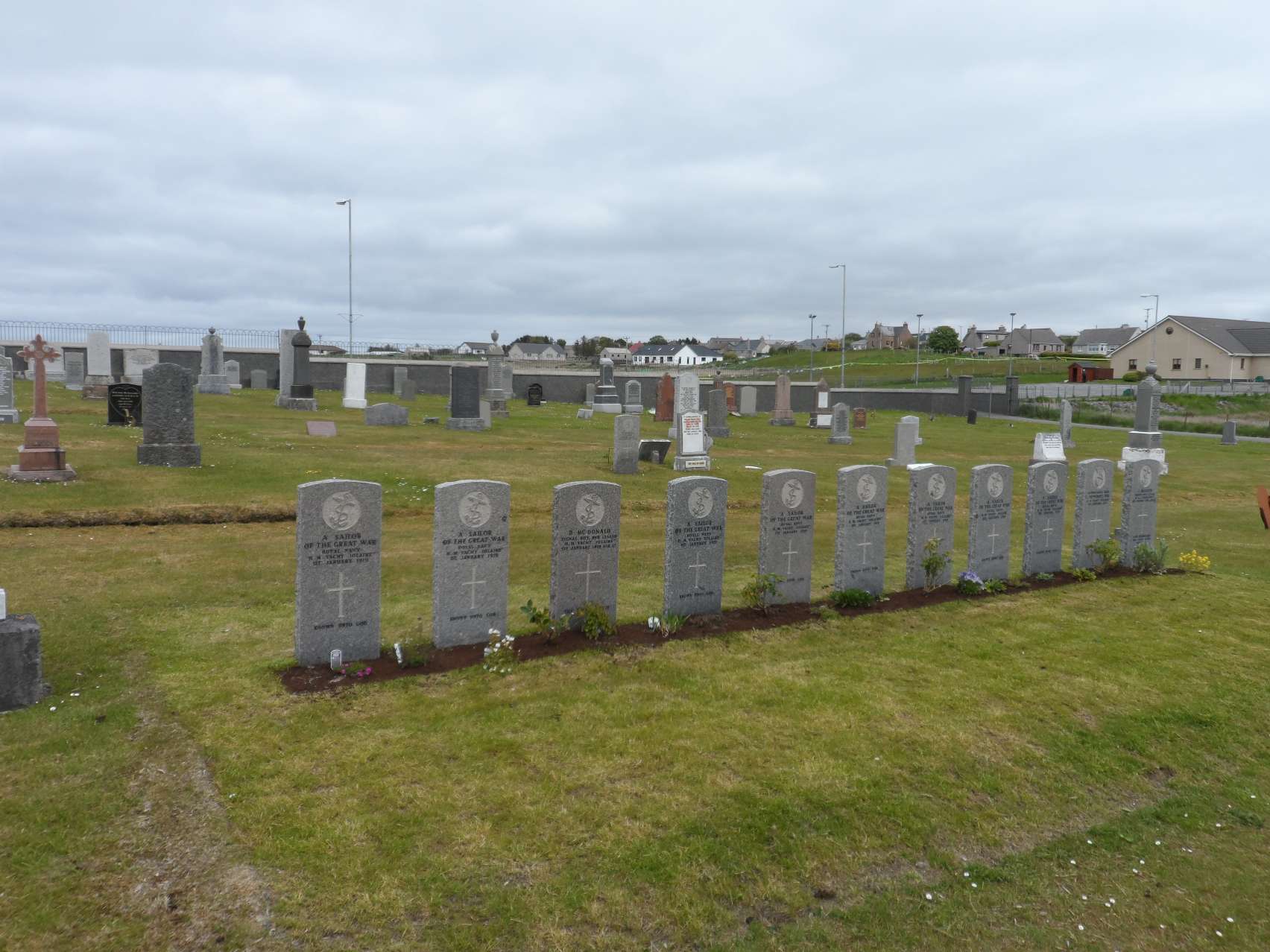 Photo of Sandwick Cemetery Stornoway. Graveyard with a row of war memorial headstones.