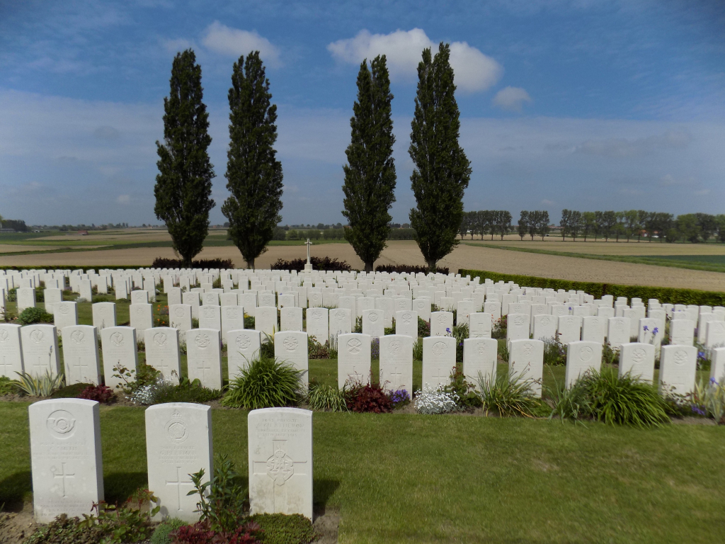 Klein-Vierstraat British Cemetery with rows of gravestones and trees in the background