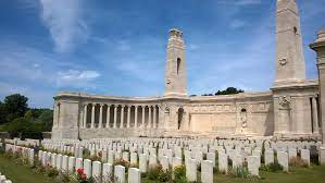 The Vis en Artois Memorial in the background with rows of gravestones in the front