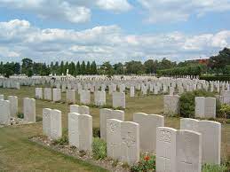 Rows of white gravestones surrounded by plants and mown grass