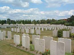 Rows of white gravestones surrounded by plants and mown grass