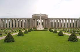 mown grass interspersed with small conical bushes leads to a colonnaded structure in white