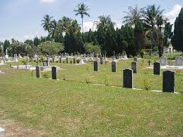 gravestones surrounded by mown grass with trees in the background