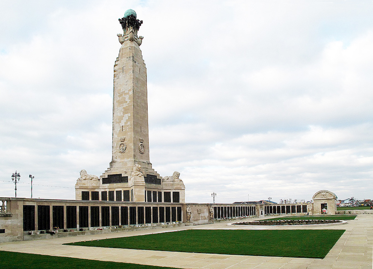 a large white column with black panels underneath and strips of grass in front