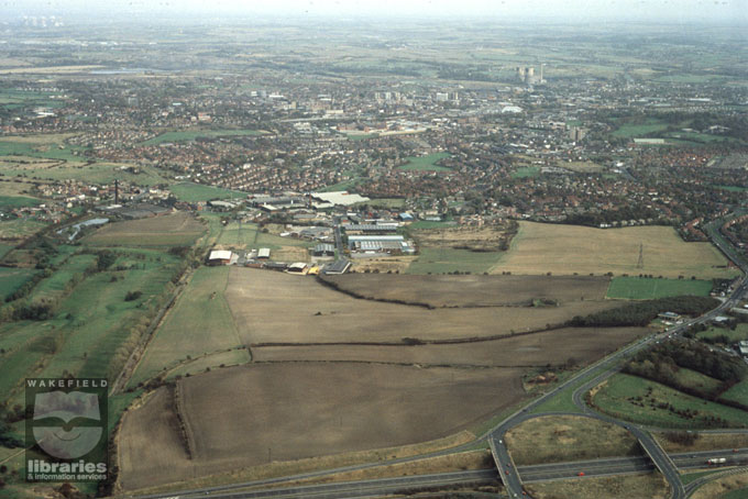 A colour aerial photograph looking towards Wakefield City Centre.  Wakefield Power Station at Agbrigg, demolished in 1994, is in the far background on the right.  Wakefield Road is on the right, where it crosses over the M1 motorway.  Internal Reference: WR (LS)