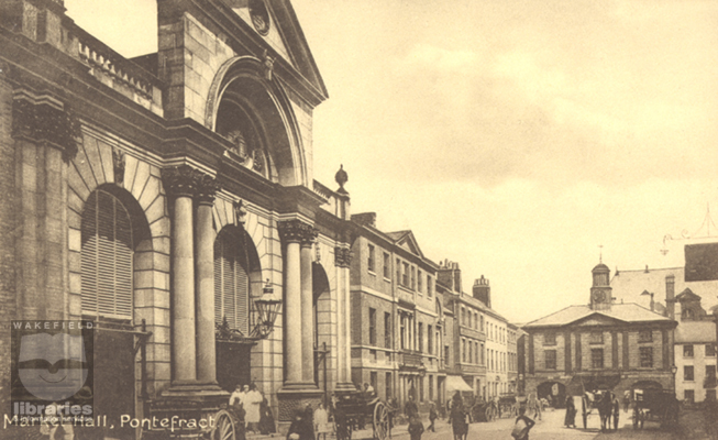 A black and white postcard of the market hall and Town Hall, Market Place, Pontefract.  This was taken before the frontage was altered and then lowered.  The ventilation burres can be seen as can part of the pediment.  The Red Lion Hotel is also visible.  Internal Reference: PO B76