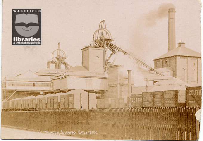 A sepia postcard which shows a view of South Kirkby Colliery buildings in front of which are both incoming and outgoing trains.  The pit head machinery can be seen in the centre and the left side which would have been used to lift coal to the surface and to transport the miners.  The postcard is postmarked 'South Kirkby'. Internal Reference: Private Collection