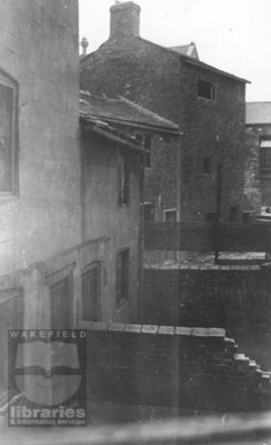 Houses in Camplin Yard and Greenhill Road, Eastmoor, 1930-1935 A black and white photograph showing numbers 9 and 11, Camplin Yard, off Stanley Road and the back of numbers 17 and 21 Greenhill Road, Eastmoor. The houses were built in close proximity, and were derelict when the photograph was taken between 1930 and 1935. Saint Andrew's Elementary School, Greenhill Road, can be seen on the far right. The houses were demolished on the 14th August 1935. Internal Reference: WR 103, 363.5 WAKW, Photographs of Slum Clearance Properties Book 2