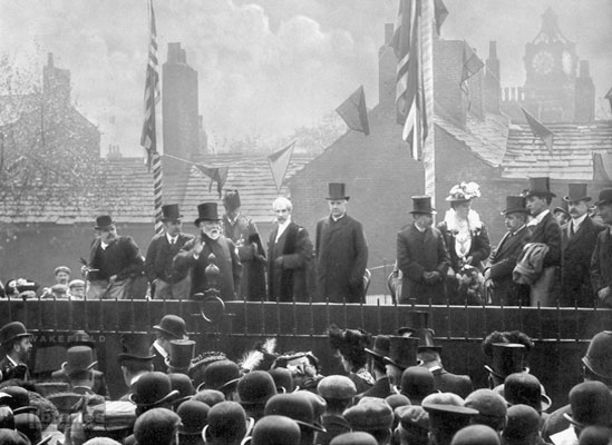 The opening ceremony of Wakefield Free Library on Drury Lane, Wakefield, June 2nd 1906 A black and white photograph showing the opening ceremony of Wakefield Free Library on Drury Lane, Wakefield, on the 2nd of June 1906. Mr Andrew Carnegie accompanied by the Mayor and other officials can be seen making a speech. Carnegie donated £8,000 to build the library. The Skidmore Library Collection of Wakefield books - now held at Balne Lane Library- was unveiled at the ceremony. C.R.Wordsworth is in the invalid chair on the left. Internal Reference: WR(LS)