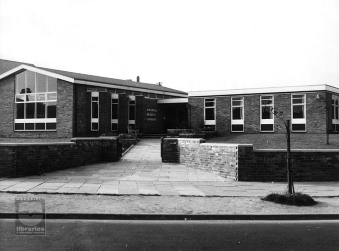 A black and white photograph looking from the gates, up the path to the front of Airedale Branch Library.  The library was opened in April 1962 and has since suffered fire damage and was later demolished, rebuilt and reopened in 2002.  Internal Reference: CA YILLUS 796