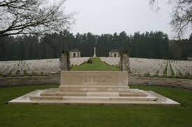 a stone slab reads their name liveth forever more and rows of white gravestones are behind. in the distance are trees